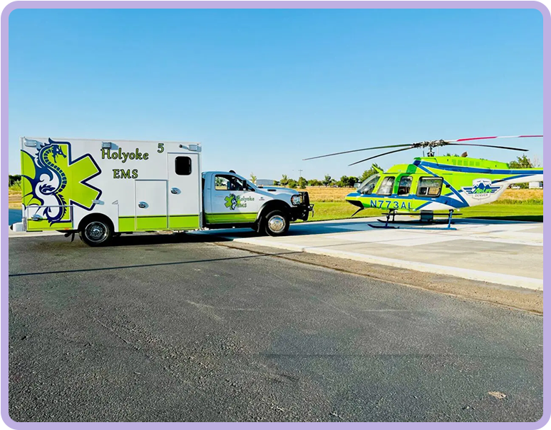 A large ambulance and helicopter parked on the side of a road.
