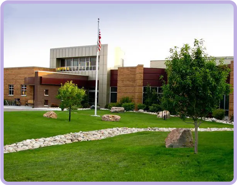 A large building with trees and rocks in front of it.