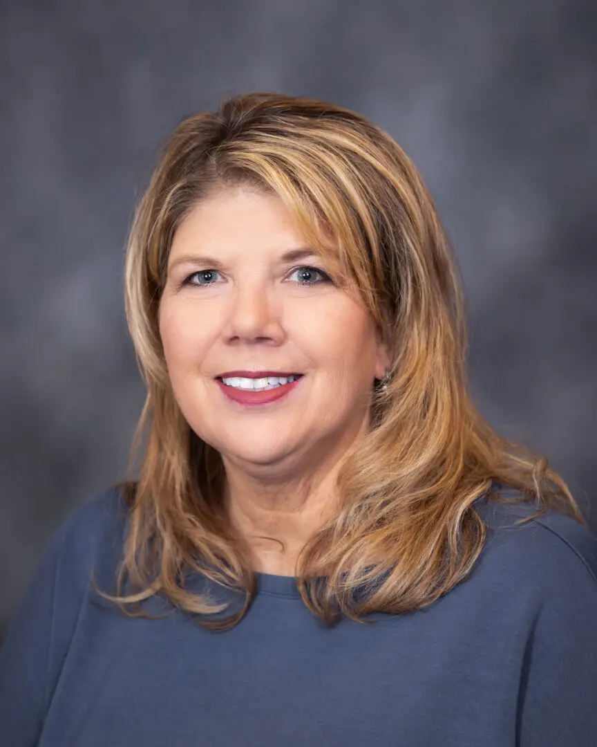 A woman with long blonde hair and blue shirt.