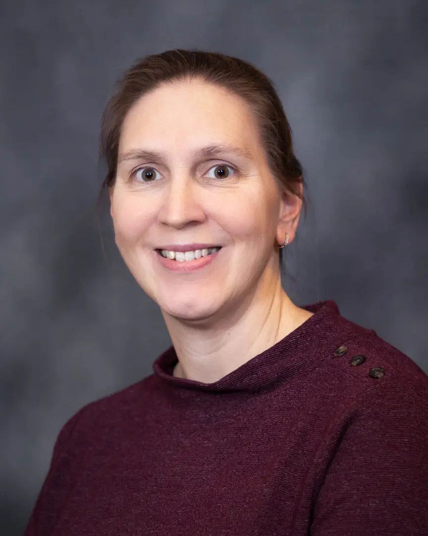 A woman in maroon shirt smiling for the camera.